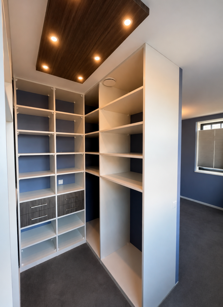 Stijlvolle walk-in closet gebruikt als roomdivider tussen slaapkamer en kleedruimte.