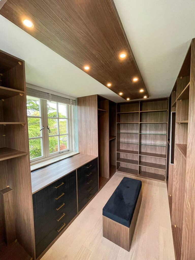 Luxe walk-in closet in Amerikaanse stijl met open vakkenkasten, lades en sfeervolle lichtkoof