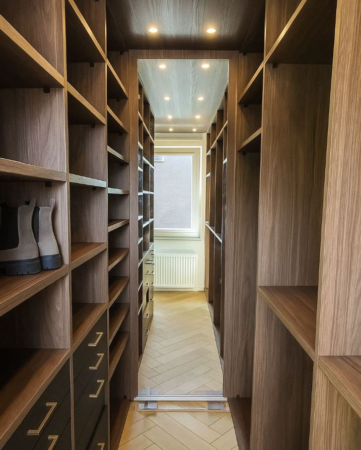 Luxe walk-in closet met ingebouwde spiegel, open vakkenkasten en kledingroedes.